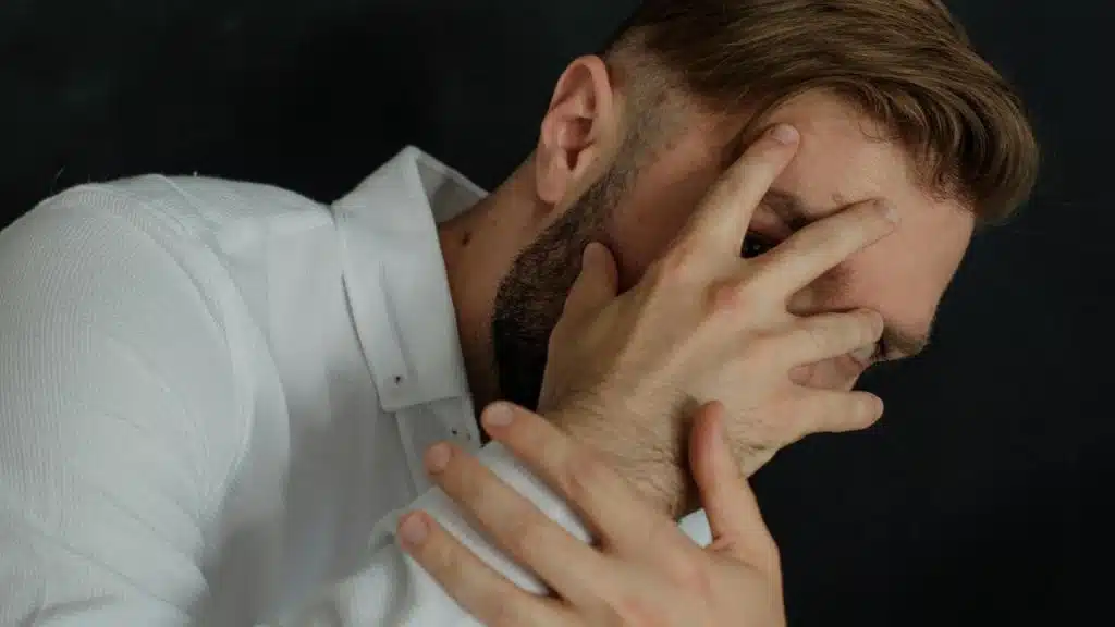 A man covering his face with his hand in distress.