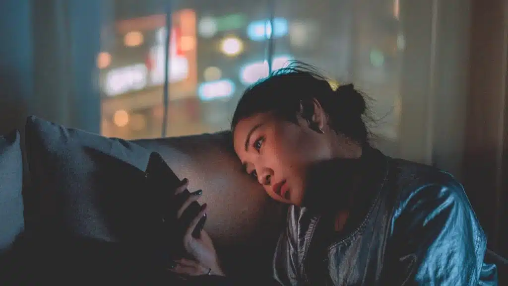 A woman using a phone in a dimly lit room.