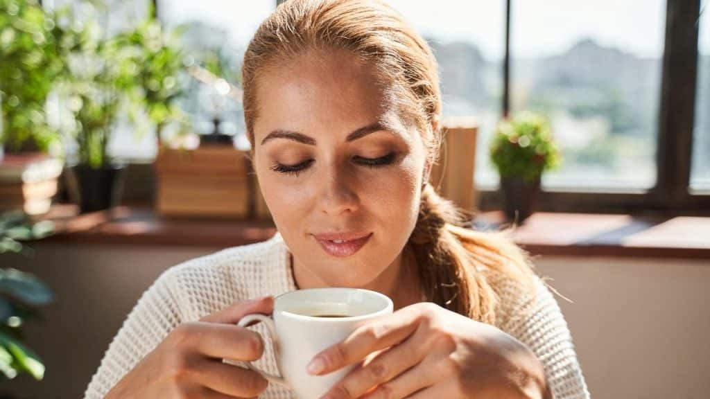 A woman enjoying a cup of coffee indoors.