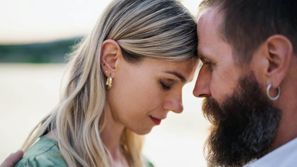 A man with beared and a blonde woman are embracing each other.
