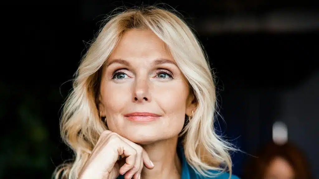 A woman smiling slightly and looking thoughtful.