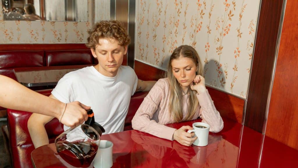 A waiter serving coffee to a couple in a restaurant.