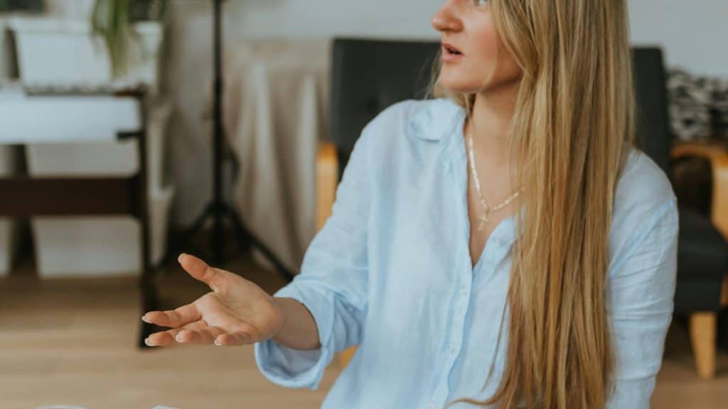 A woman gesturing with her hand while speaking indoors.