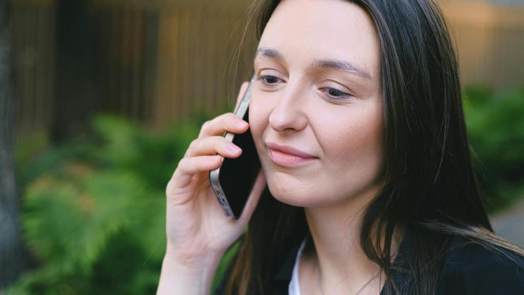 A woman smiling while talking on her phone outdoors.