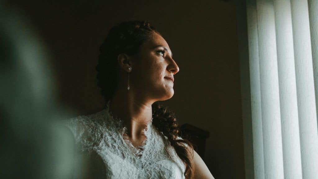 A bride looking towards a window.