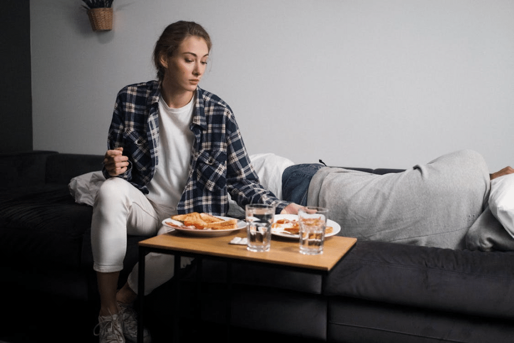 Woman Giving Food to a Man on a Sofa