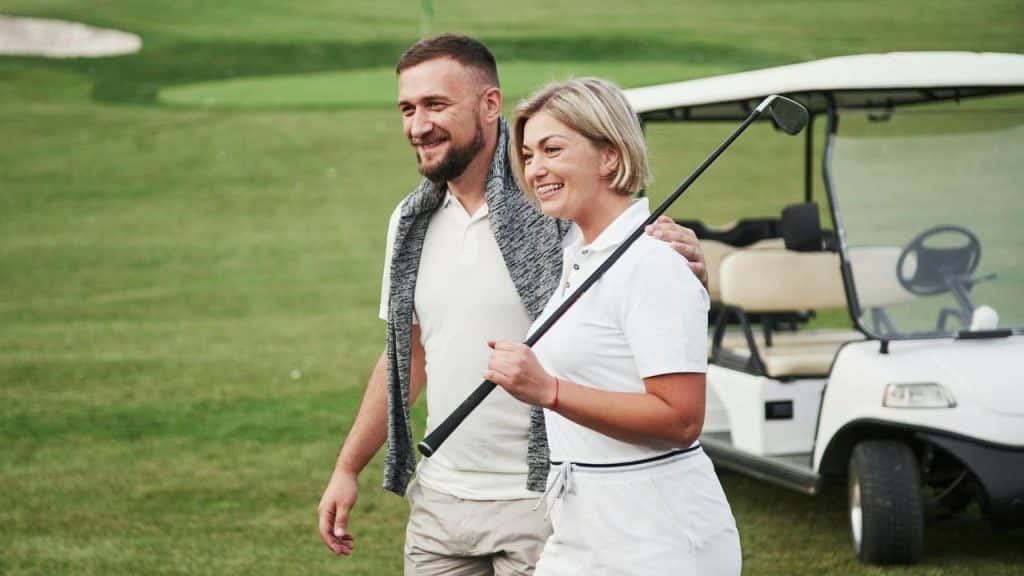 A smiling couple walking together on a golf course.