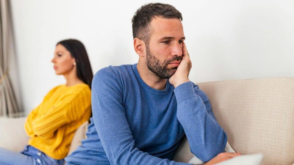 A young couple sitting on a couch after having argument