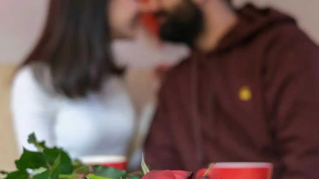 A blurred couple sitting together with a rose in the foreground.