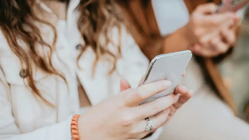 A closeup picture of a woman holding a white cell phone.