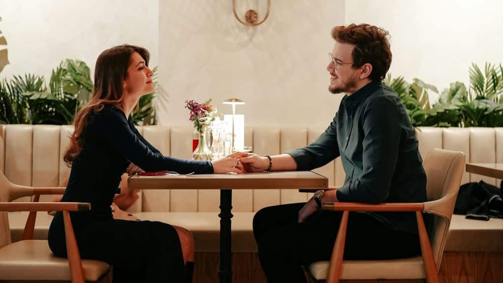 A couple holding hands while they are sitting together in a restaurant.