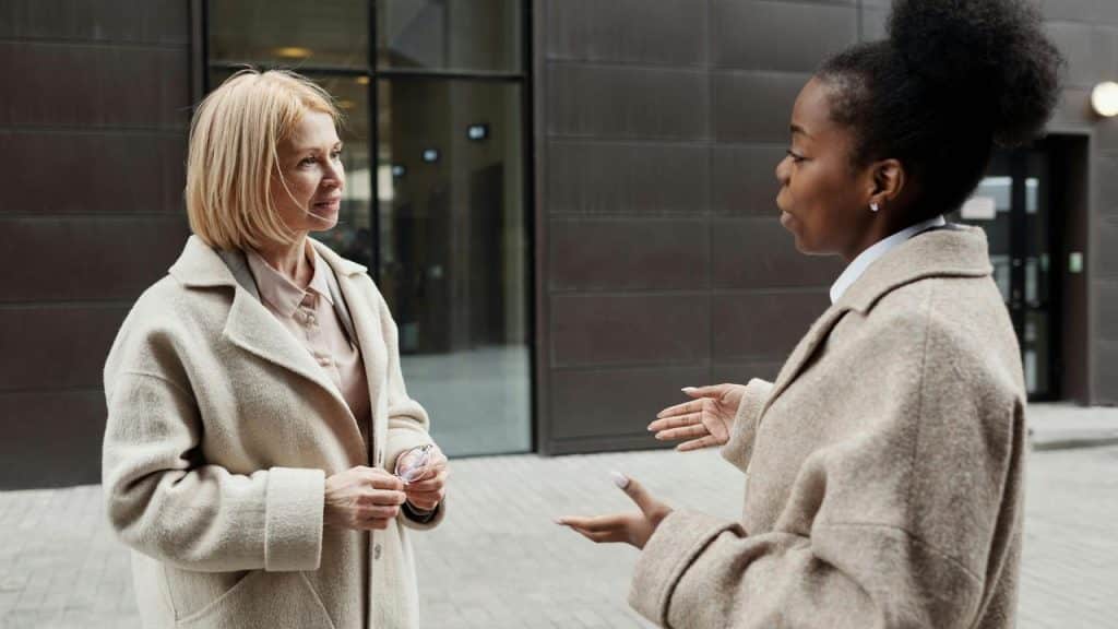 A woman talking with another woman outside a modern building.