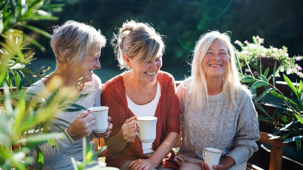 A group of mature, older friends having coffee together outdoors.