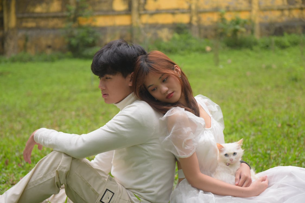 Man looking away leaning on woman with white cat