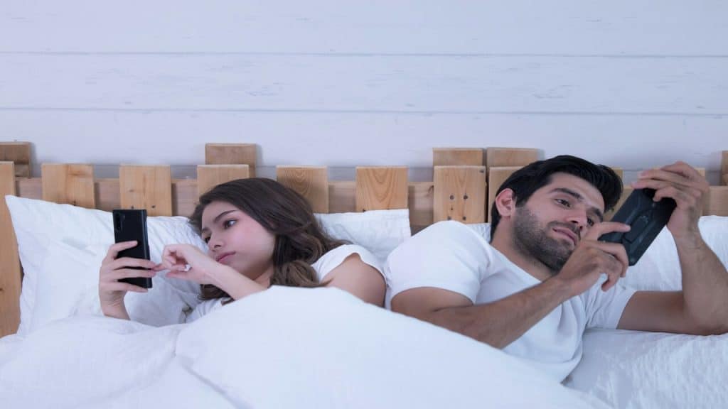 A couple using their phones in bed