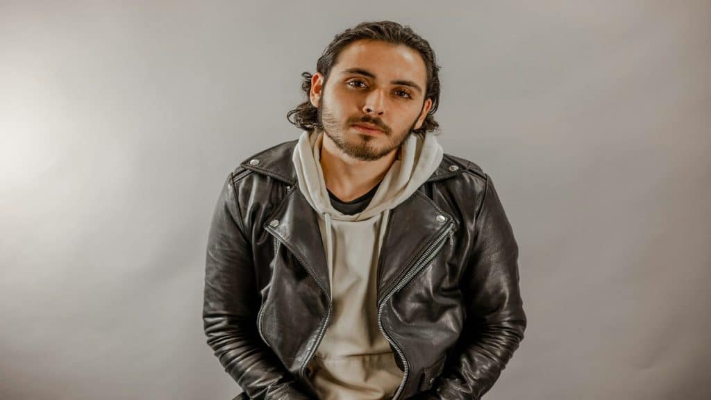 A man wearing a leather jacket and a hoodie