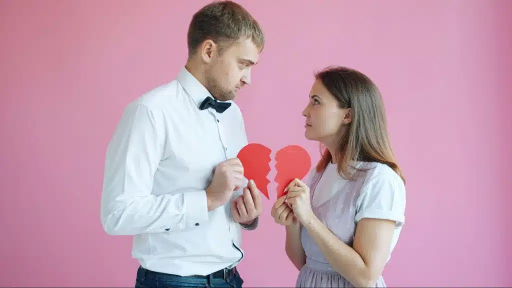 A man and woman holding a heart shaped broken paper