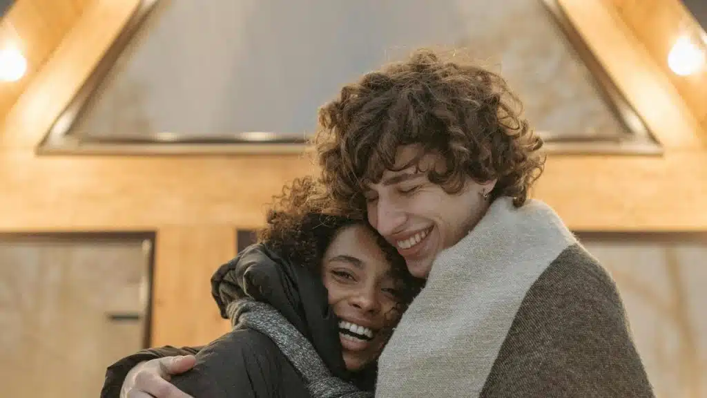 A couple hugging and smiling warmly outdoors.
