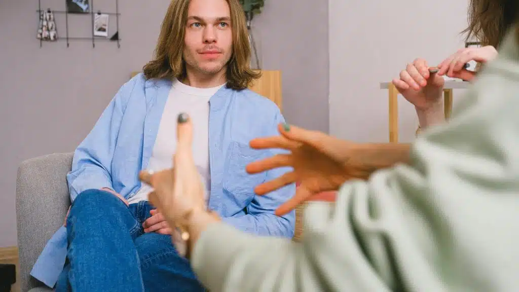 A man sitting and listening to someone speaking during a conversation.