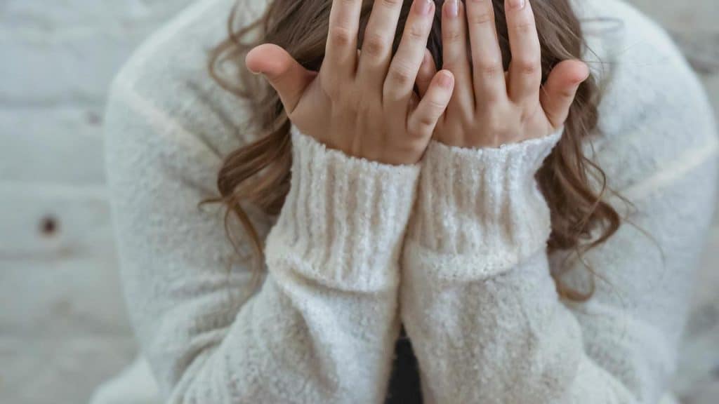A woman covering her face with her hands.