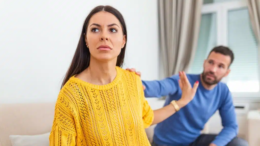 A man is touching the shoulder of a woman; the woman is gesturing to refuse to talk to him.