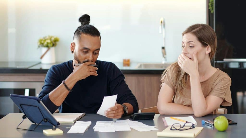 A man and woman sitting at a table looking at papers and a tablet.