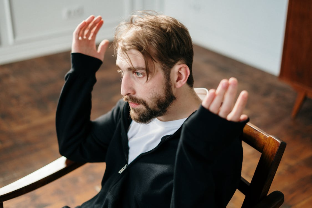Man in Black Jacket Sitting on Brown Wooden Chair