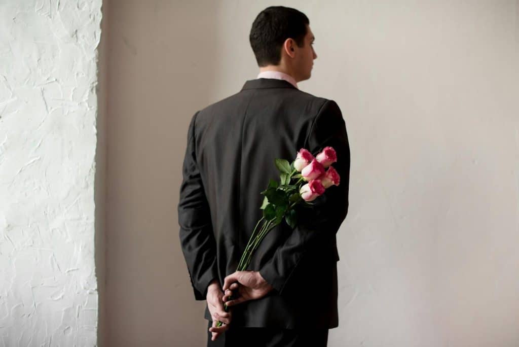 A man in a suit holding a bouquet of flowers.