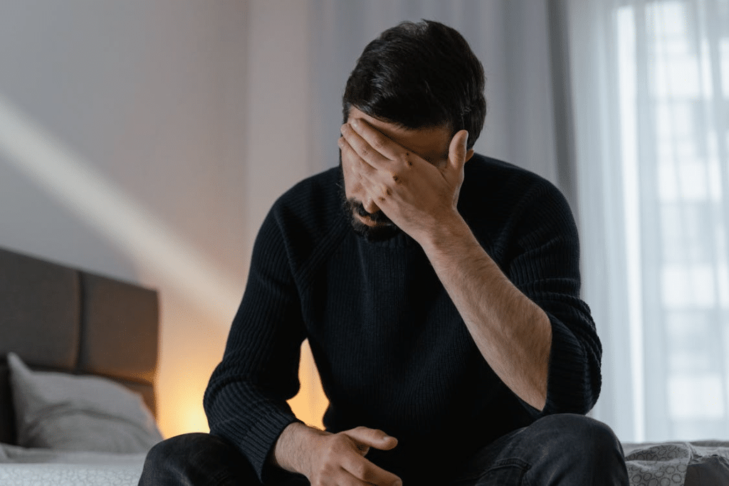 Man in Black Sweater Sitting on Bed
