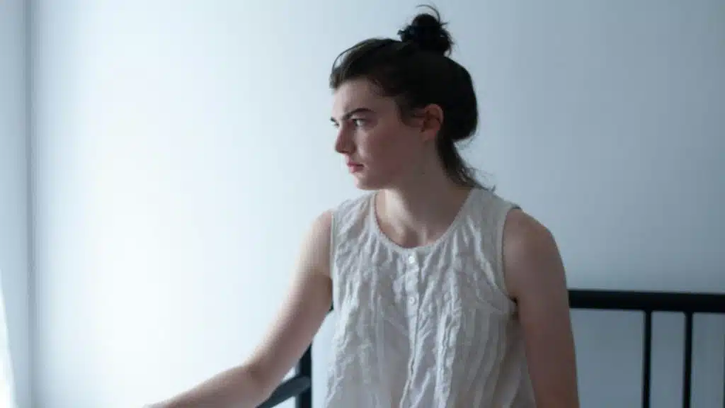 A woman sitting alone in a bedroom.