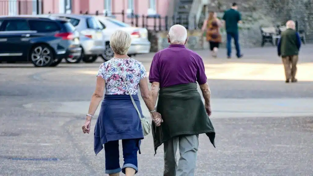 An older couple walking hand in hand on a street.