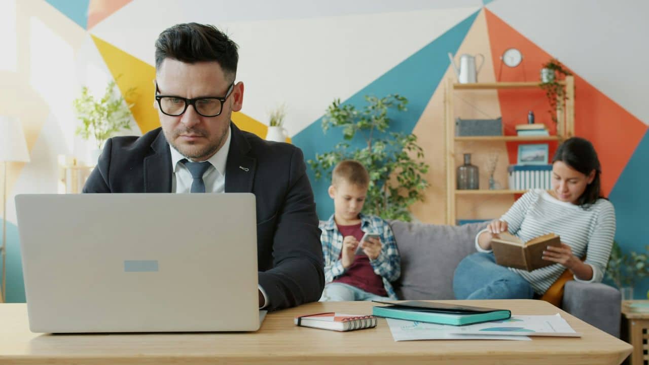 A person in a suit reviews paper documents on a wooden table with another man.