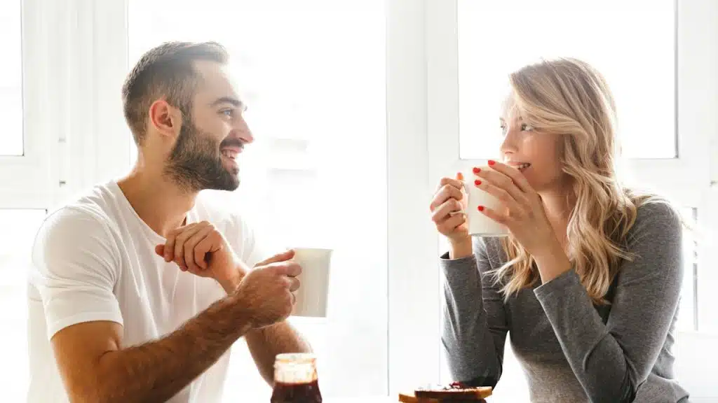 A couple is smiling while having coffee together.
