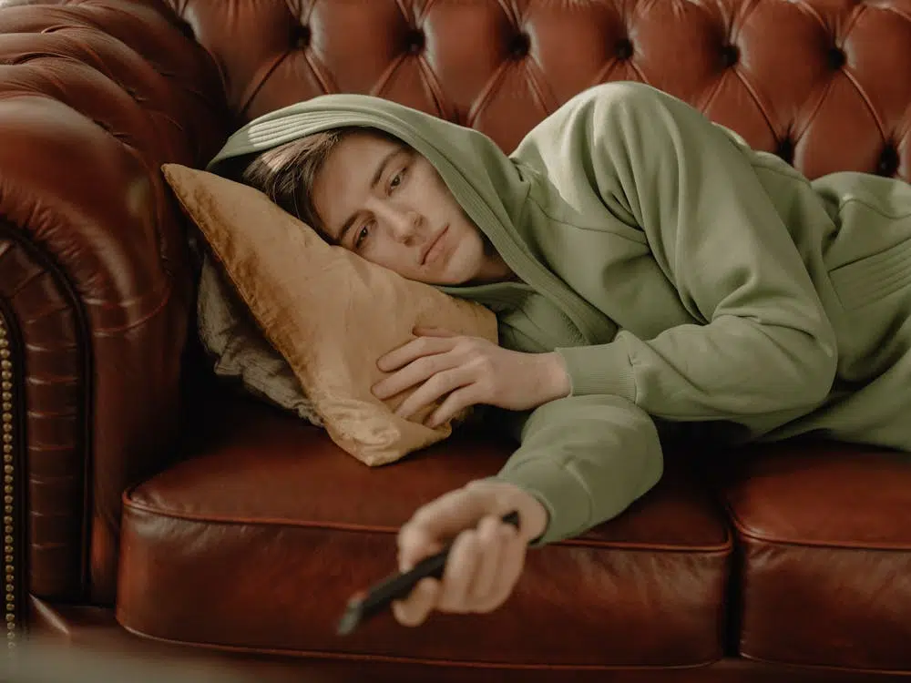 Man in Gray Hoodie Lying on Brown Leather Couch