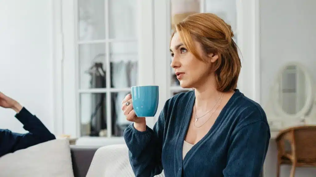 A woman holding a blue mug while sitting indoors.