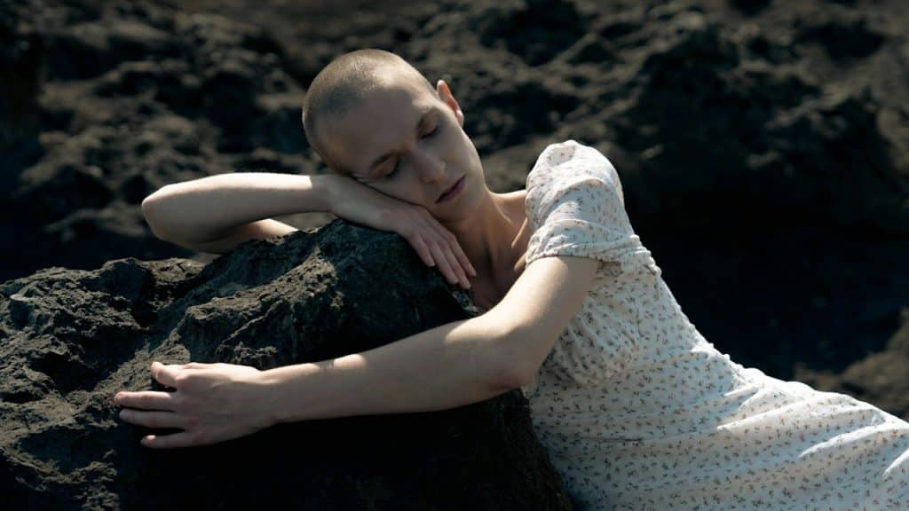 A woman lying on the top of a large rock.