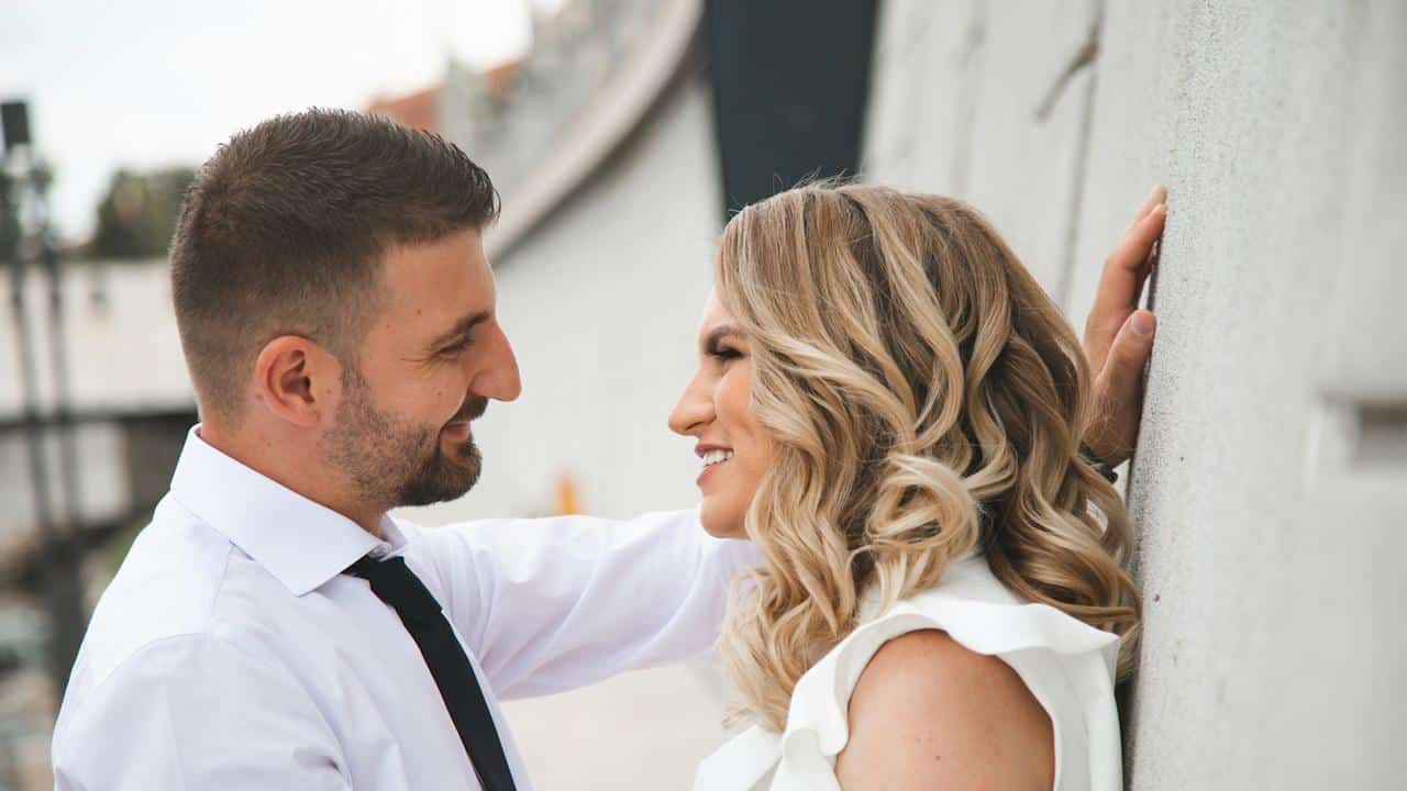 A couple smiling at each other outdoors.