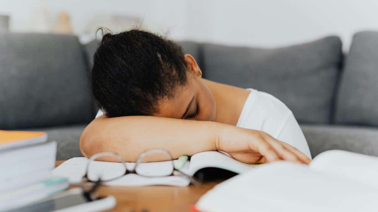 A student sleeping on an open book while studying at home.