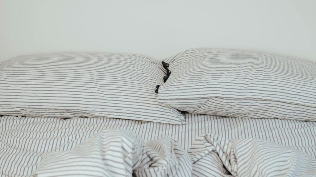 A neatly made bed with striped pillows and a matching blanket.