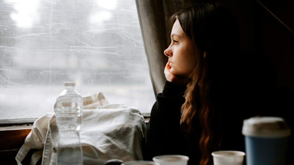 A heartbroken woman looking out of the window of a train.