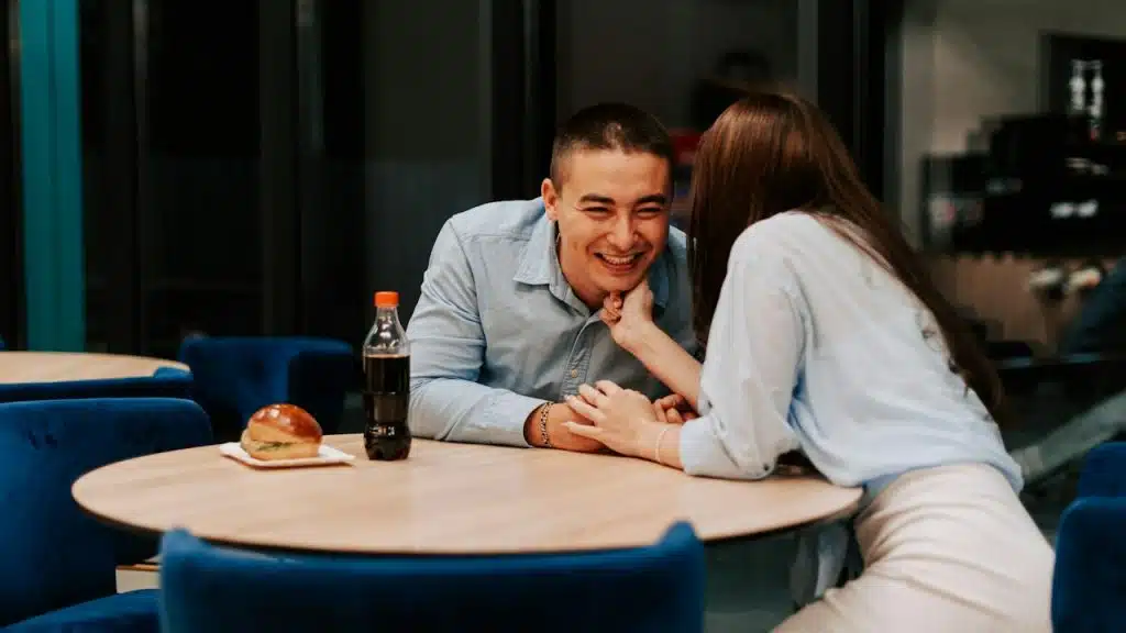 A woman whispering something in a man’s ear.