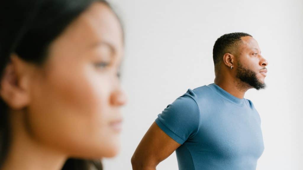 A man in a blue t-shirt looks away from a woman's blurred face in profile.