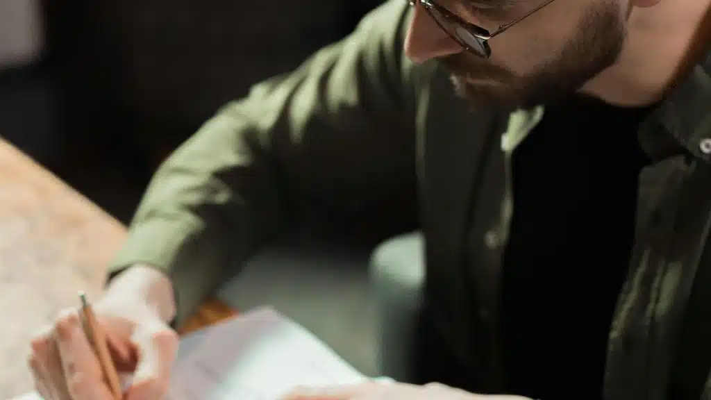 A man writing on paper at a desk.