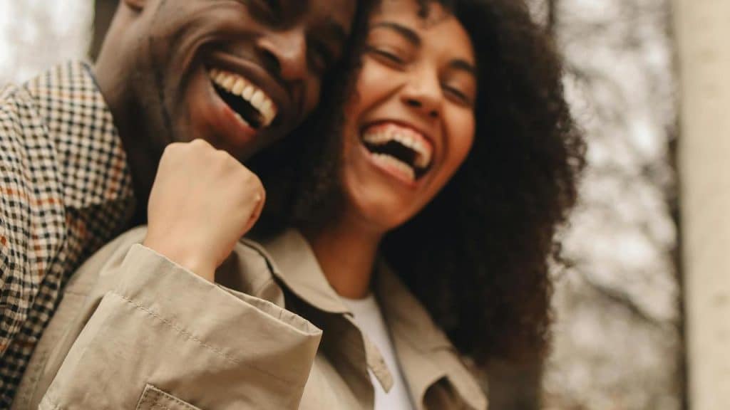A close-up of two people laughing joyfully together outdoors.