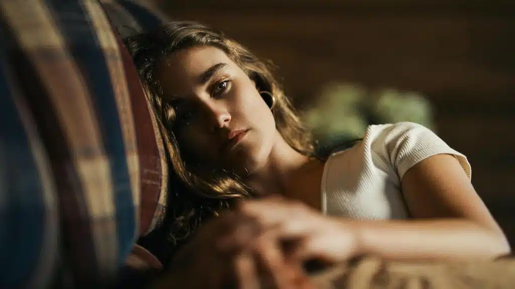 A woman lying on a couch with a tired expression.