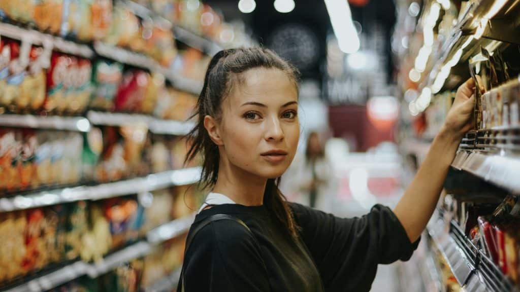 A woman shopping in a grocery store and looking at the camera.