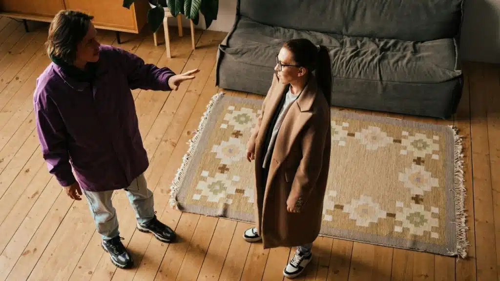 High-angle shot of a man in a purple jacket gesturing toward a woman in a tan coat.