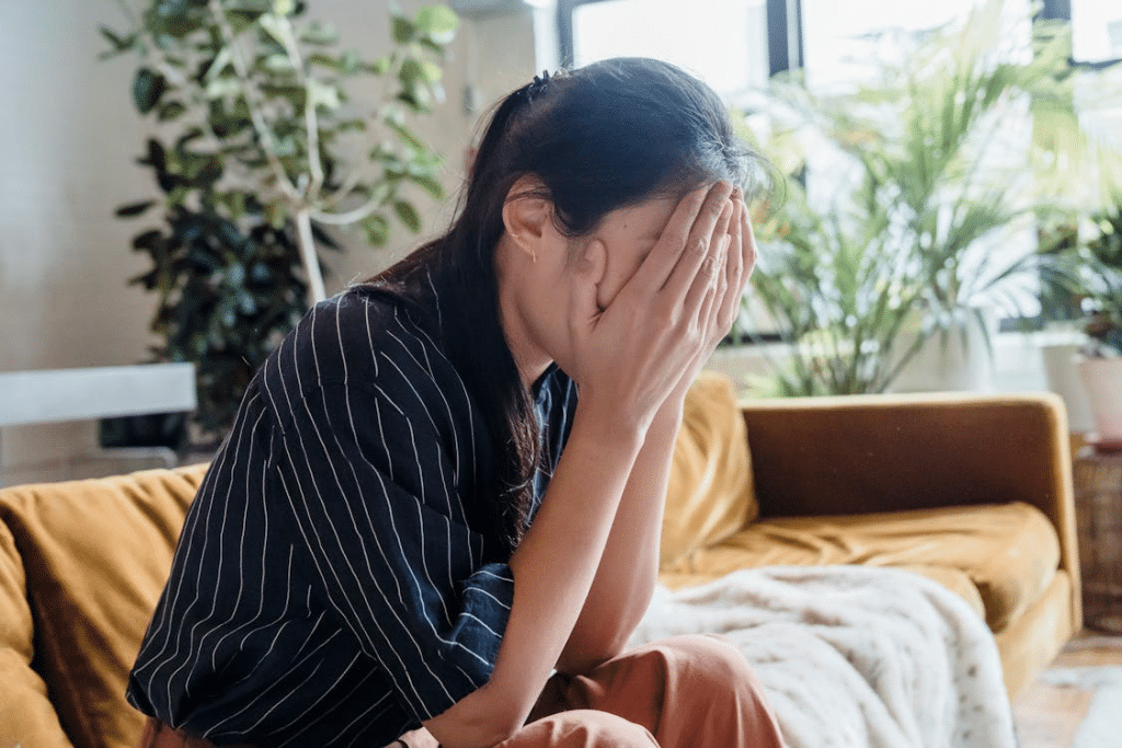 A Problematic Woman Sitting on a Couch while Covering Her Face