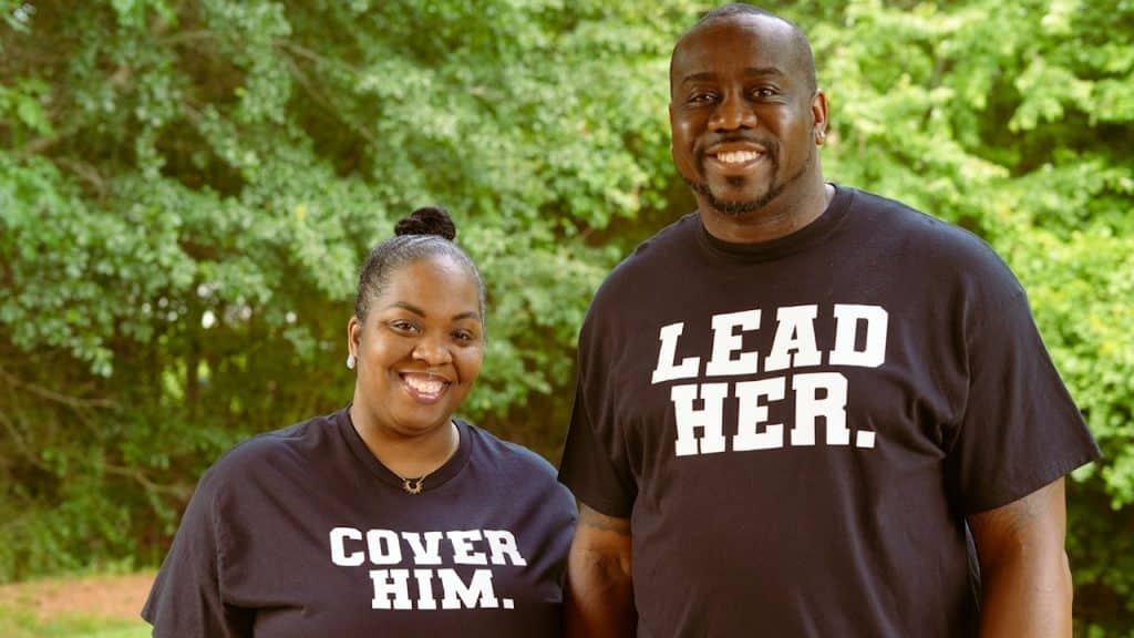 A couple wearing black t-shirts with different slogans.