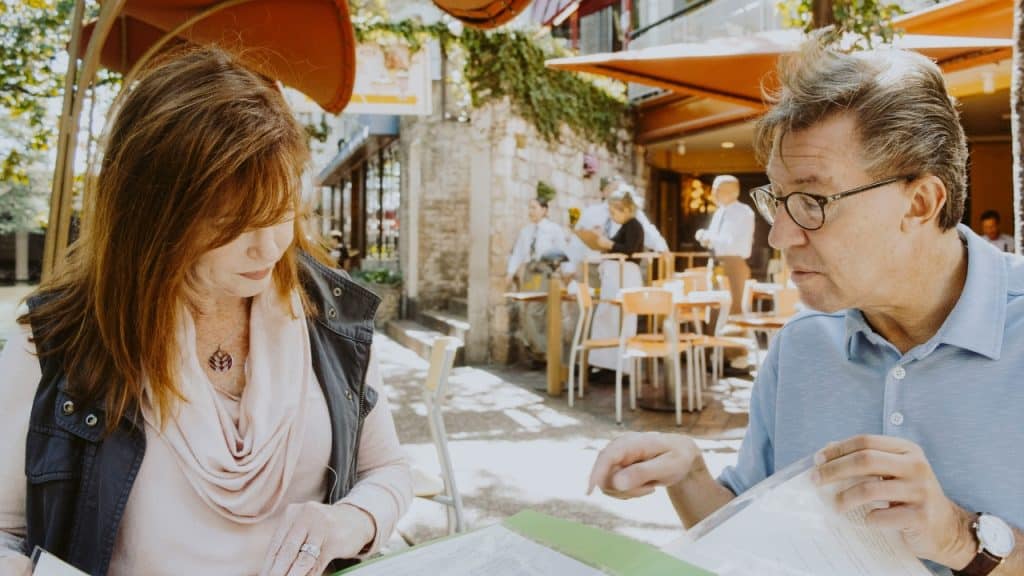 A woman with red hair and a man with glasses look at a green folder.